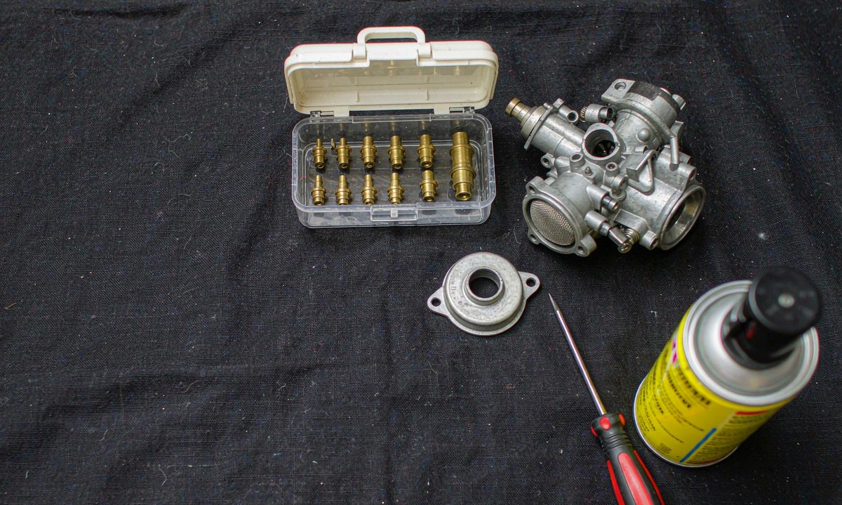 Carburetor rebuild kit laid out with jets and tools